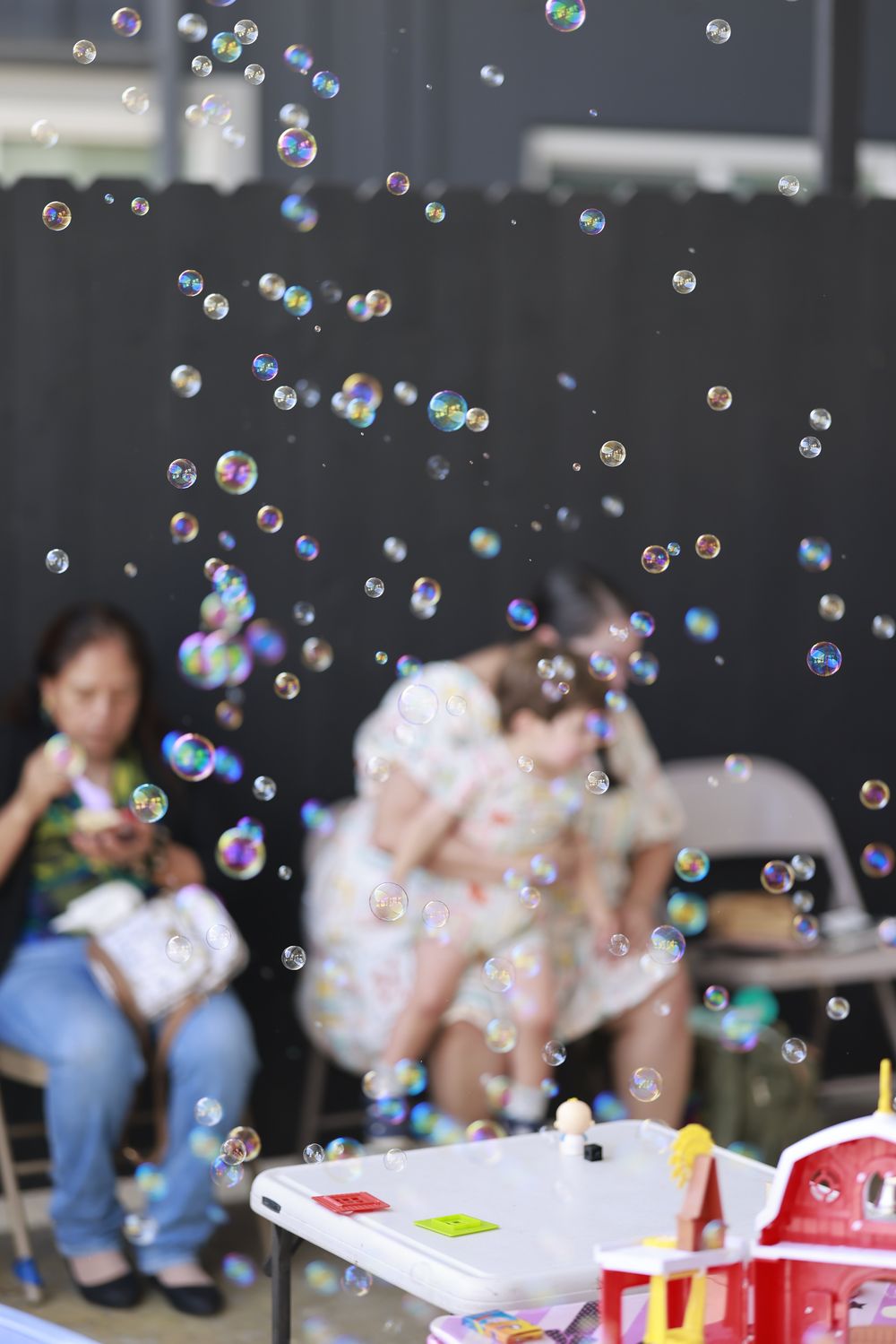 Bubbles drifting through the air as families sit together in the shade.