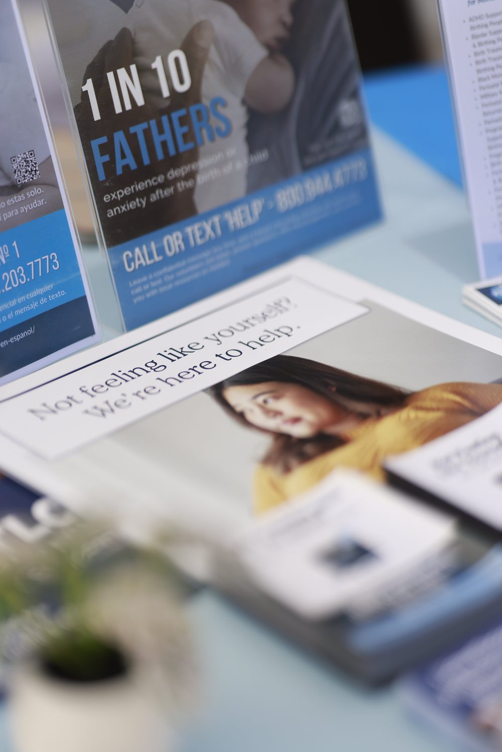 PSI materials on the table, including a card that reads 1 in 10 fathers experience depression or anxiety after the birth of a child, call or text Help to 800-944-4773.